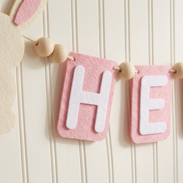 Close-up of flat pink bunny felt shapes, lettering and wooden beads